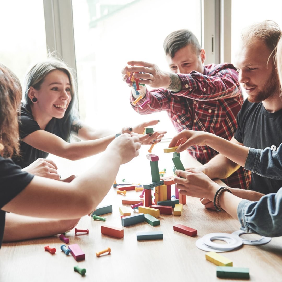 A group of creative friends sitting on a wooden table. People were having fun while playing a board game