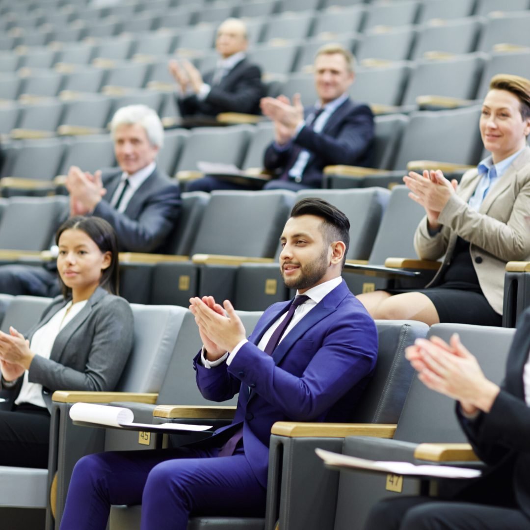 Happy audience clapping hands after speech or presentation of colleague at business conference